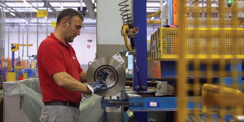 Brembo employee assembling brake disc at production station in manufacturing hall