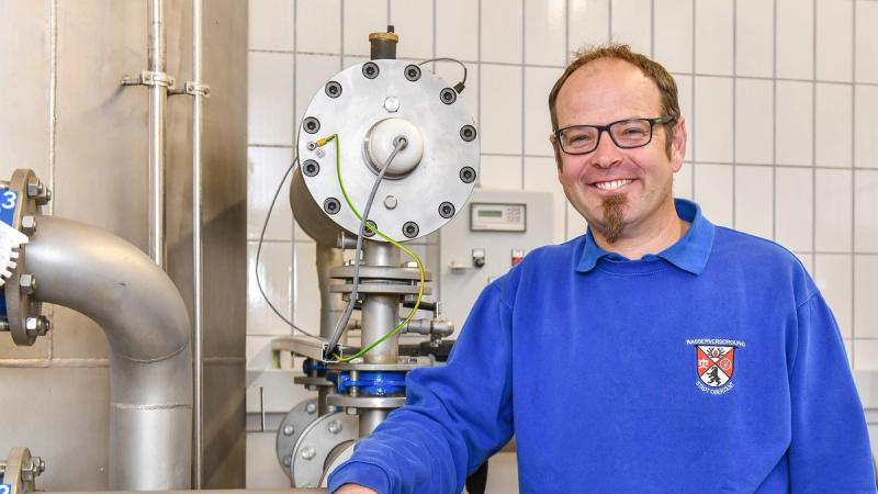 Municipal water works employee next to control valve in water supply facility