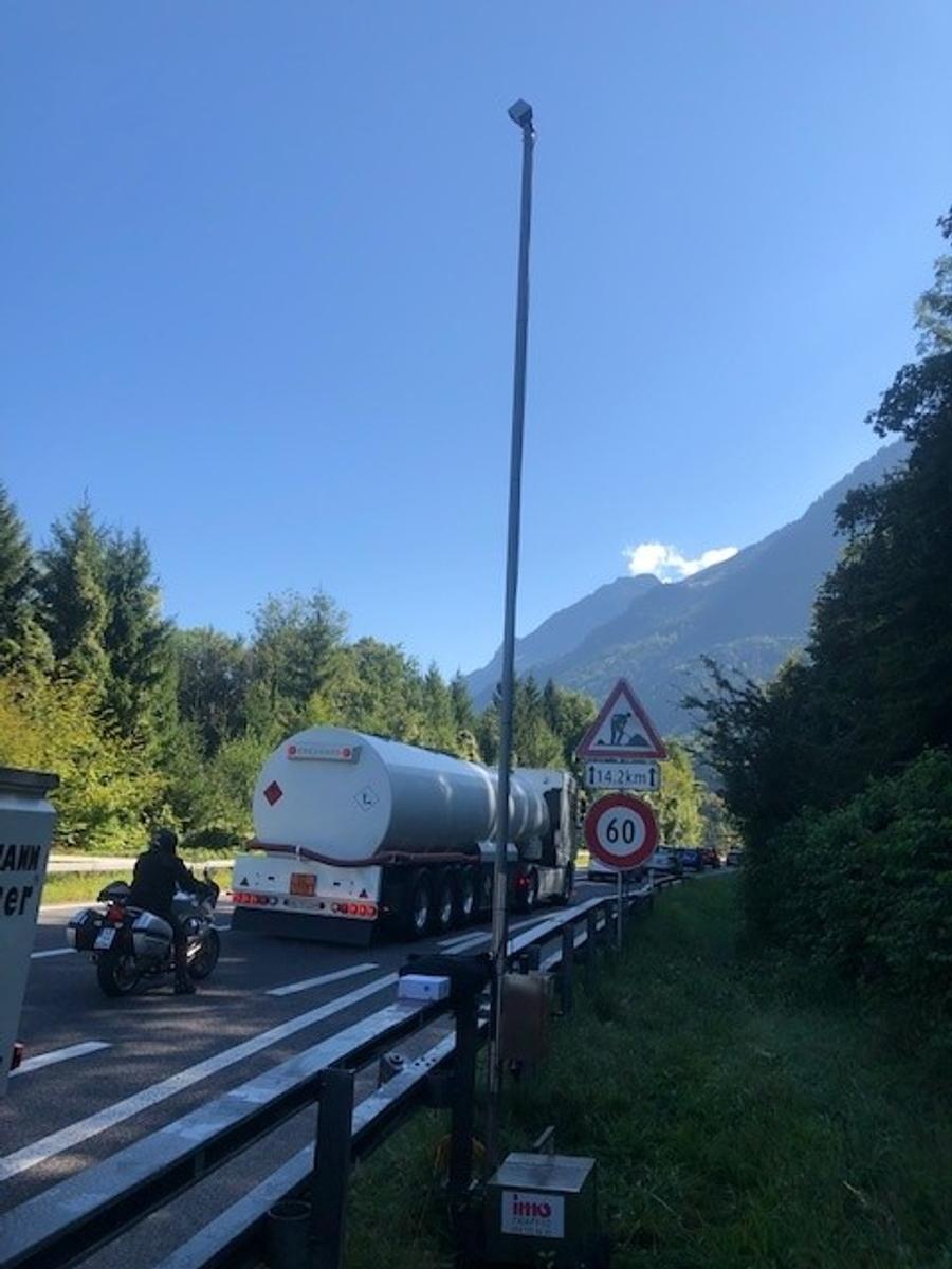 Tankwagen passiert eine Landstraße mit Tempo-60-Schild in bergiger Umgebung