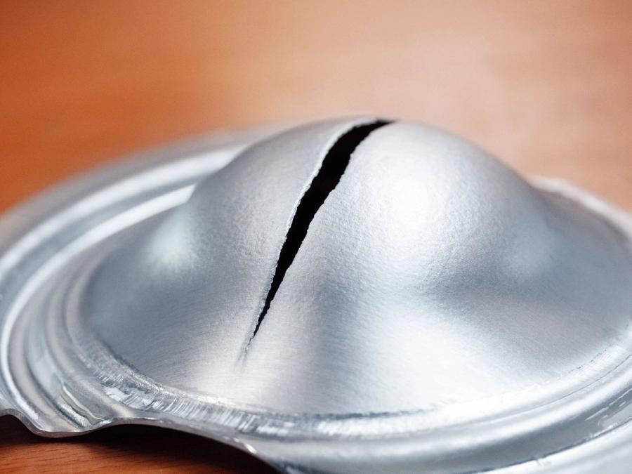 Nahaufnahme eines tiefgezogenen Metallteils mit Riss als Qualitätsfehler