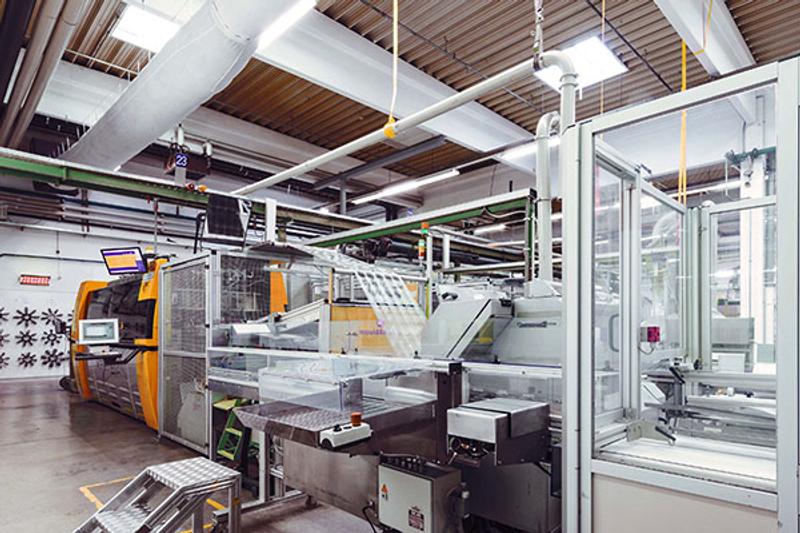 Greiner Packaging Spritzgussmaschinen-Produktionslinie mit orangen Netstal-Maschinen