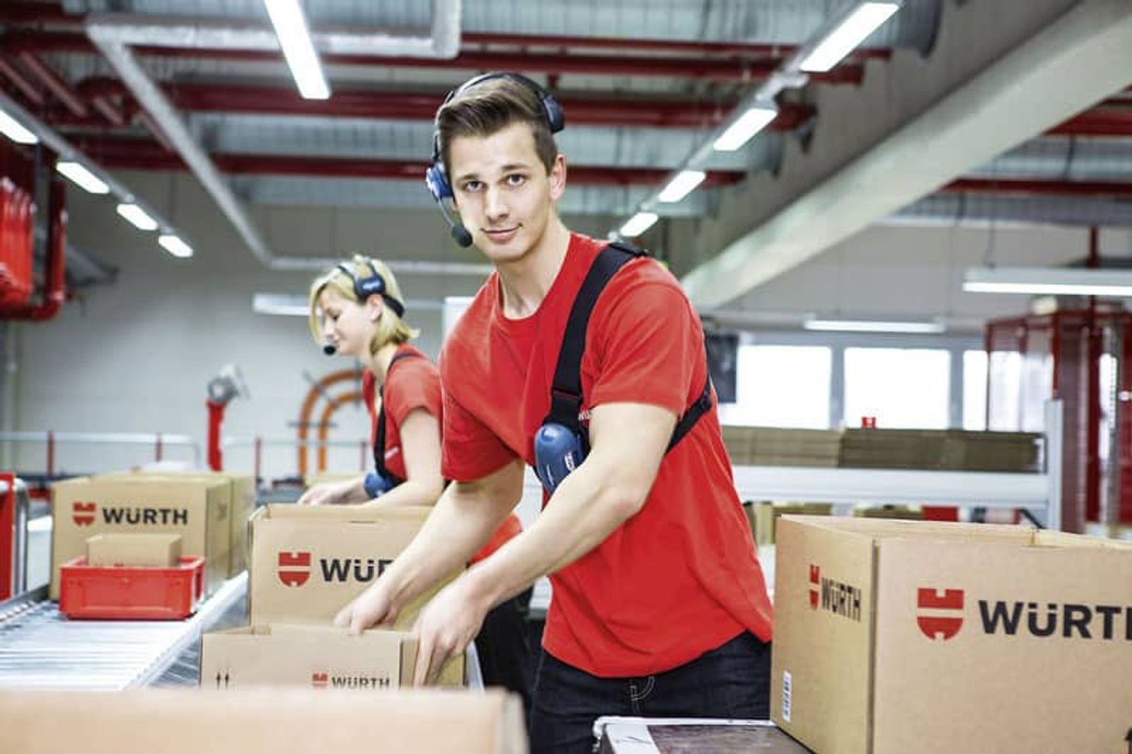 Würth packing employee sorts packages on conveyor belt in logistics center
