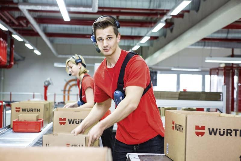 Würth packing employee sorts packages on conveyor belt in logistics center