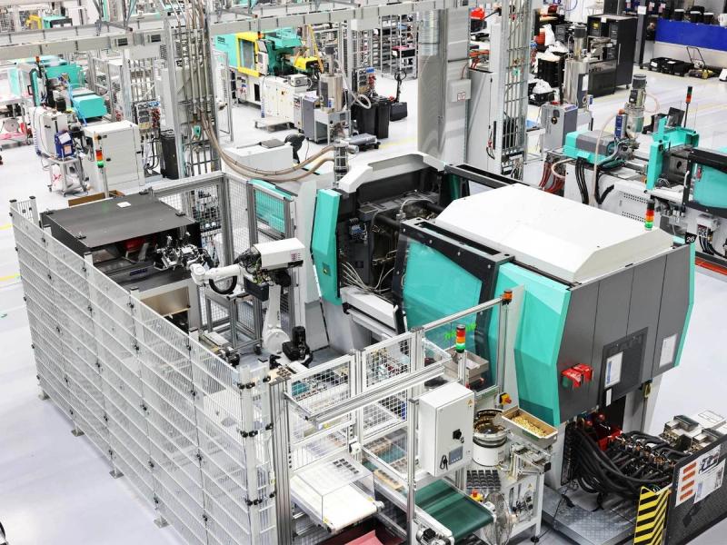 Kunststoffspritzgussmaschine mit Handlingroboter und Schutzumhausung in der Fertigungshalle von RAFI