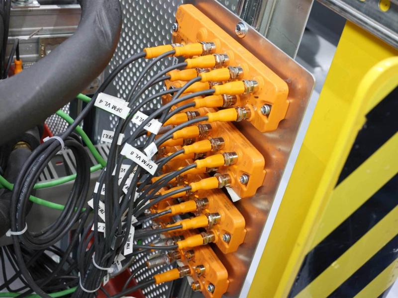 Orange IO-Link-E/A-Module AL2301 mit angeschlossenen und beschrifteten Sensorleitungen an der Spritzgussmaschine
