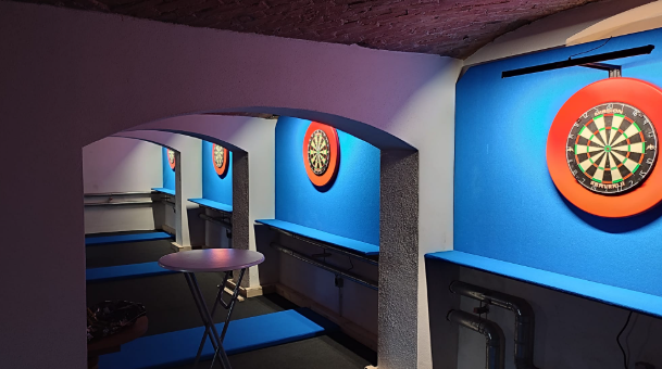 De dartruimte in het clubgebouw met twee verlichte dartborden