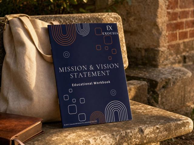 The Mission & Vision Statement workbook propped on an old stone bench in a church courtyard at golden hour, beside a canvas tote.