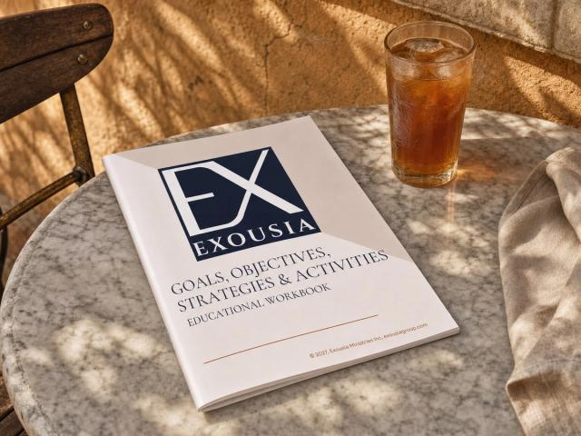 The Goals, Objectives, Strategies & Activities workbook on a marble café table in dappled afternoon sun, beside a glass of iced tea.