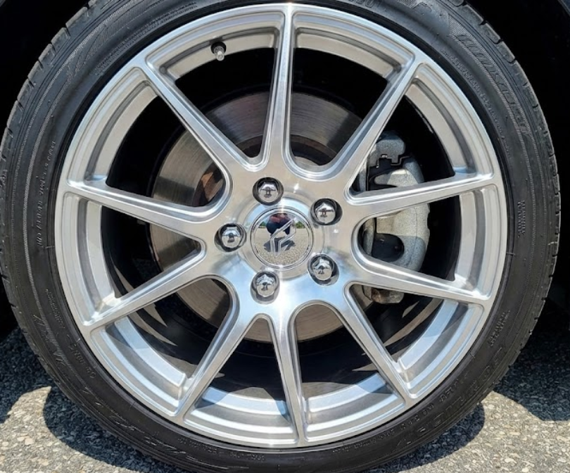 Świeżo zamontowana alufelga z nowym, błyszczącym dekielkiem centralnym i nakładkami na śruby.