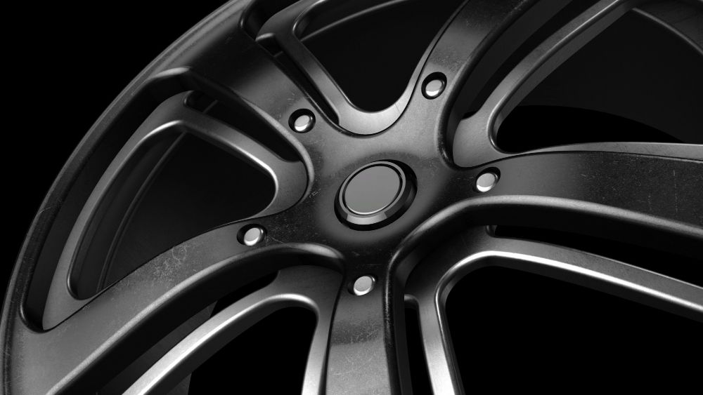 Black matte aluminum wheels with double five spokes on a dark sports car. Dynamic shot.