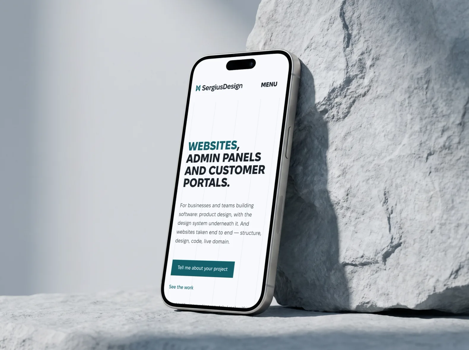 Phone against a pale stone with the sergiusdesign.com home page in English: the headline “Websites, admin panels and customer portals” and the “Tell me about your project” button