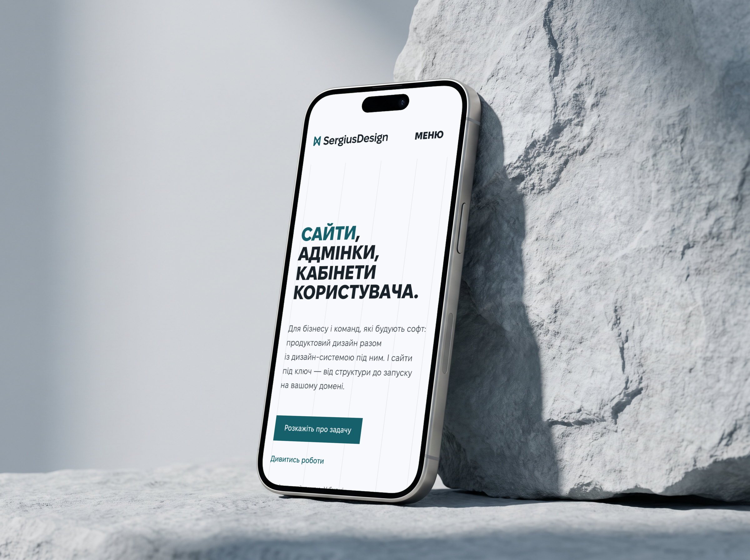 Телефон біля світлого каменя з головною sergiusdesign.com українською: заголовок «Сайти, адмінки, кабінети користувача» і кнопка «Розкажіть про задачу»