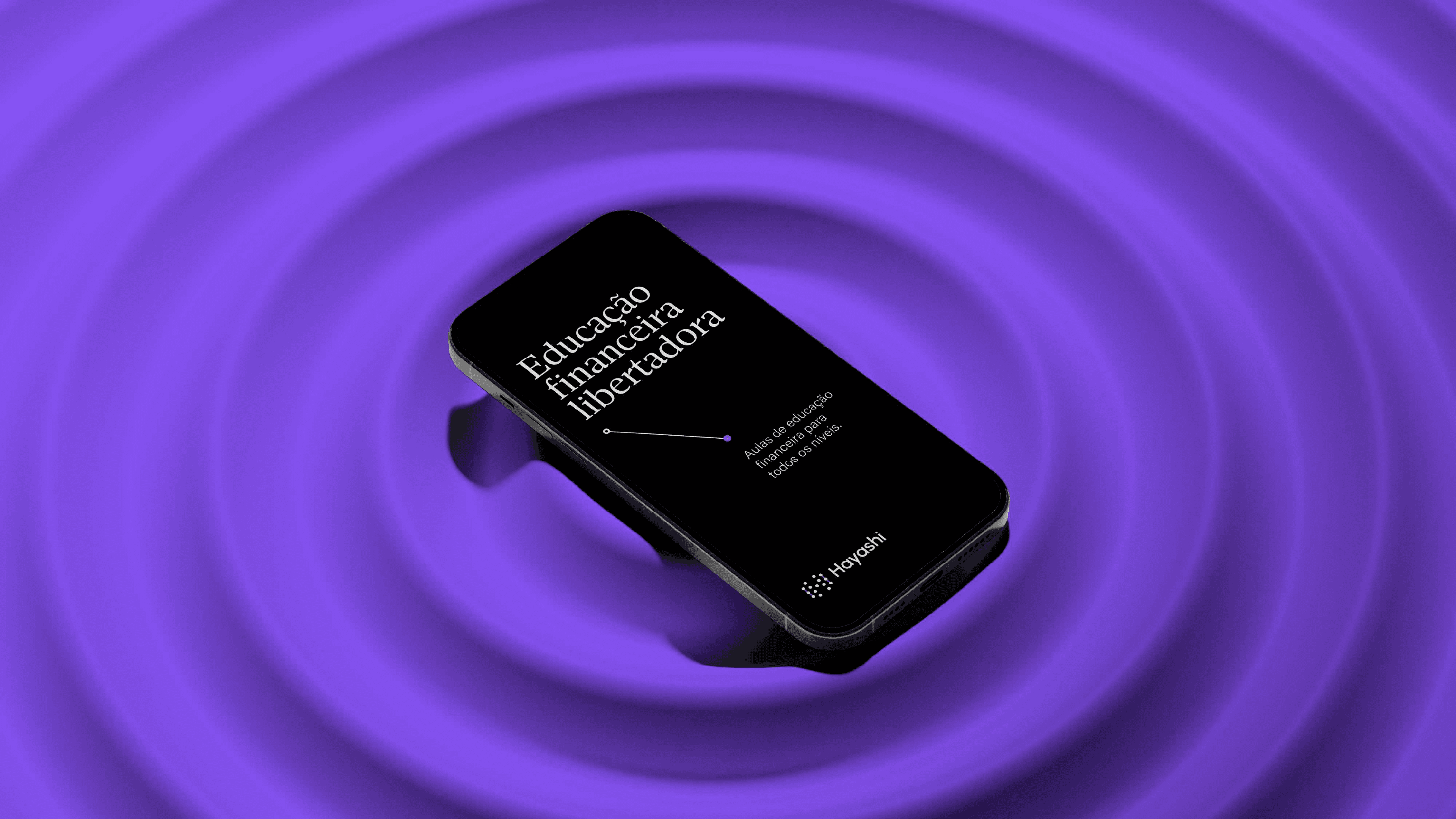 Celular preto sobre fundo roxo em ondas concêntricas, tela com Educação financeira libertadora e o logo Hayashi.