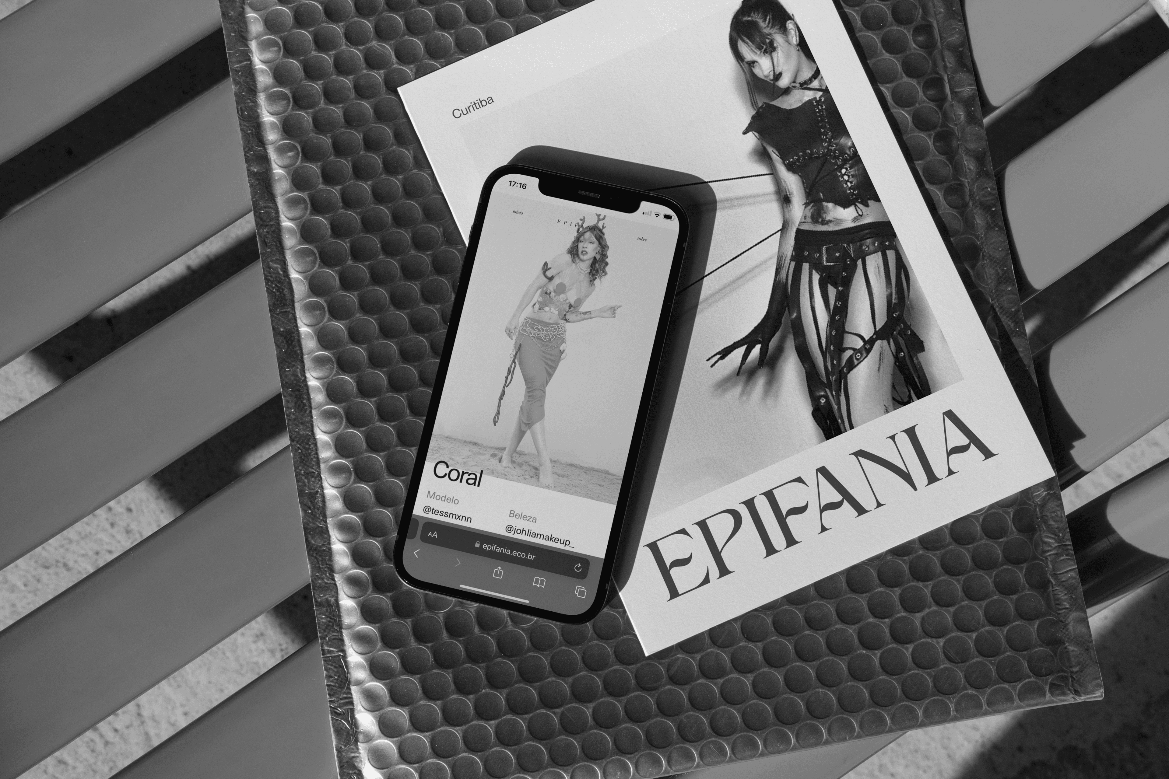 Celular sobre a revista Epifania em envelope bolha, tela com o look Coral, tudo em preto e branco.