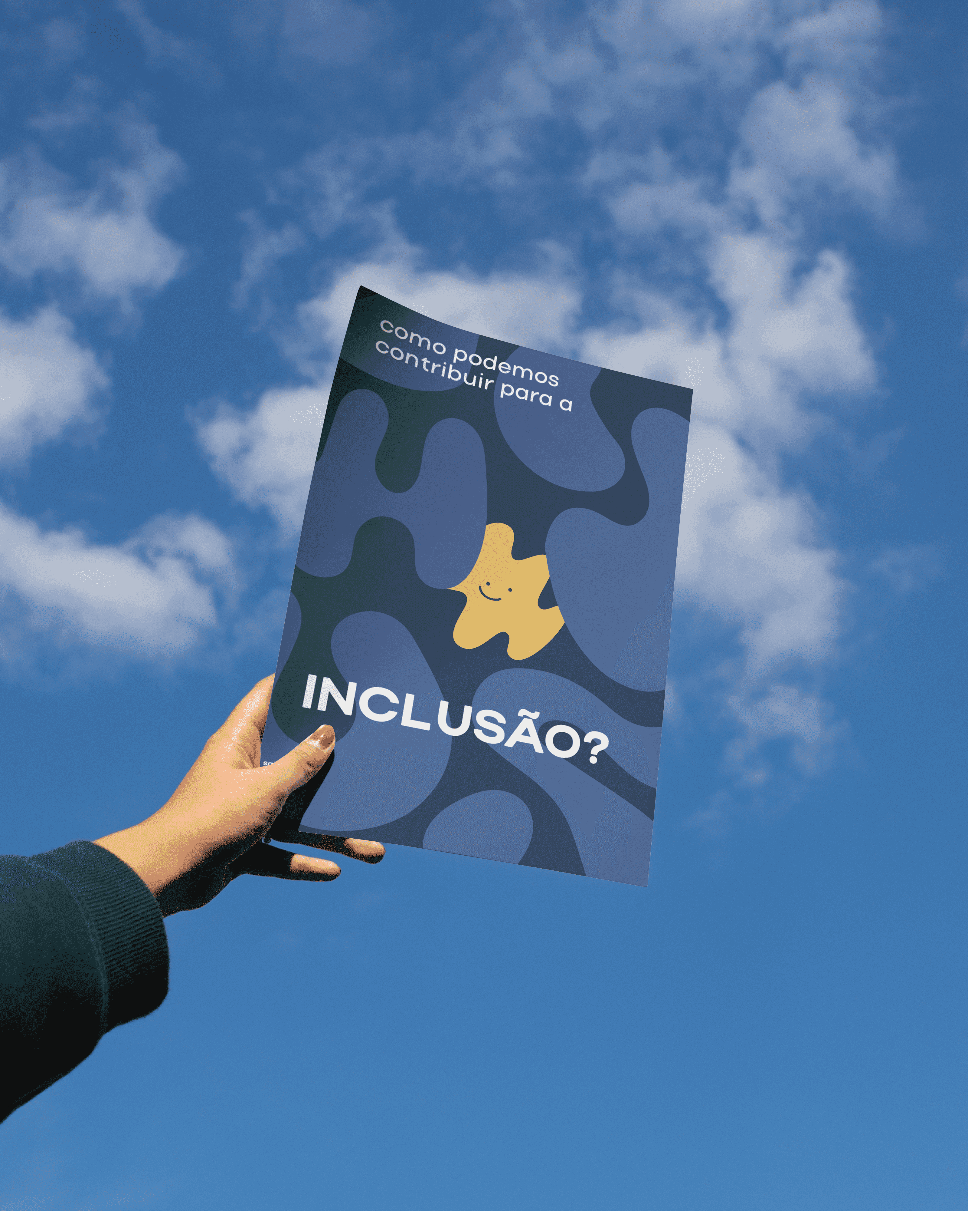 Cartaz erguido contra o céu azul, formas de quebra-cabeça em azul e uma peça amarela sorridente perguntando como podemos contribuir para a inclusão