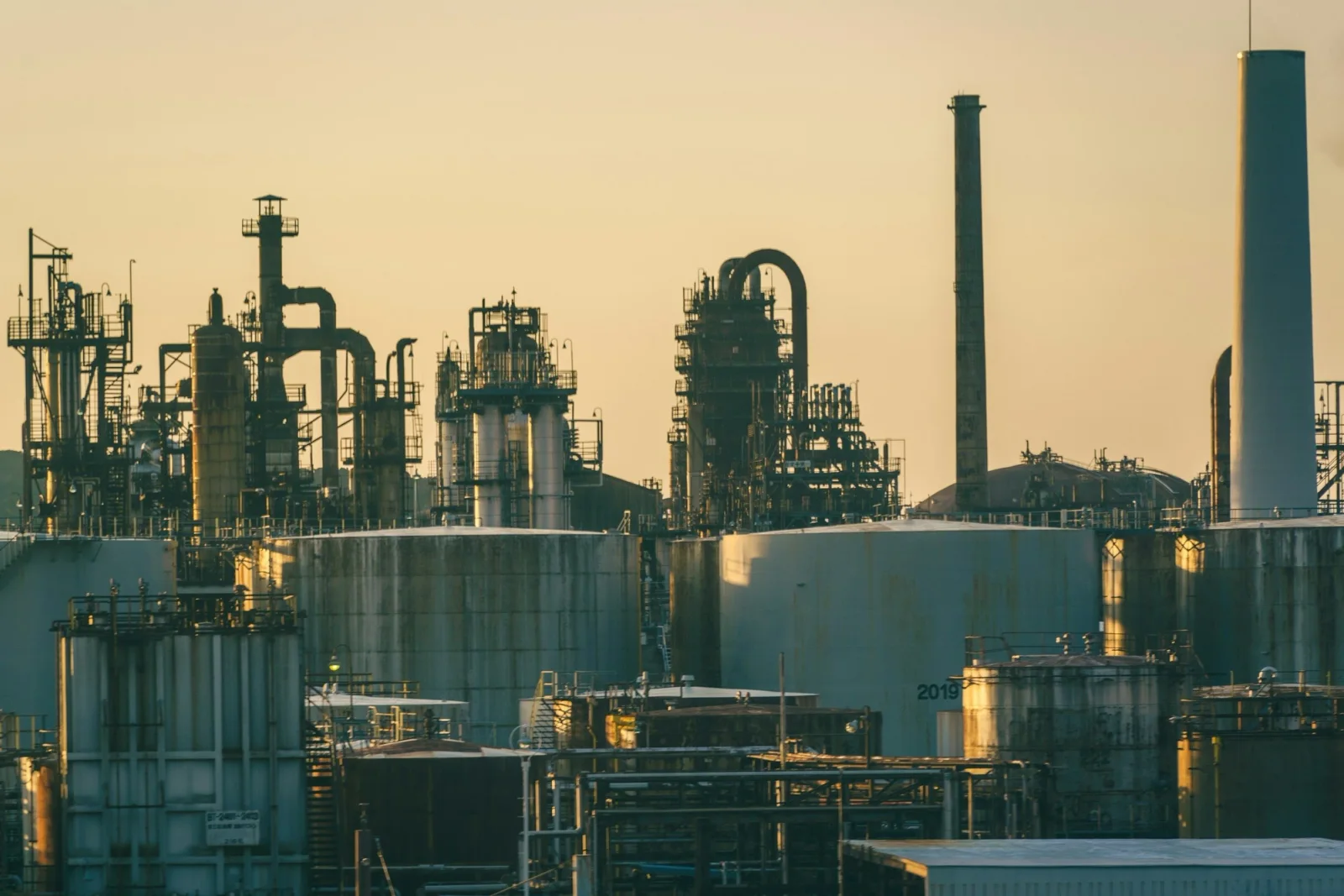 A refinery at dusk: distillation columns, flare stacks and storage tanks