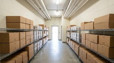 Tidy back-of-house dry store corridor lined with chrome shelving of cartons and clear bins
