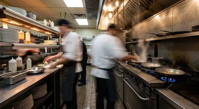 Long exposure of cooks moving along a busy restaurant hot line, figures blurred into motion streaks
