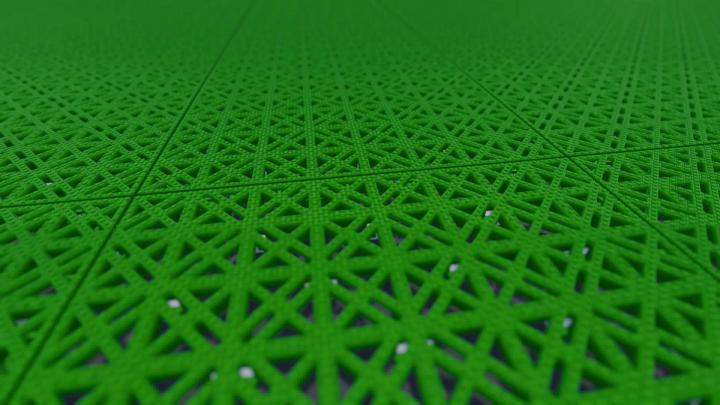 Close-up of green modular sports tiles, showing the open lattice pattern that lets the surface drain through itself.