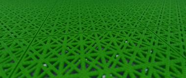 Close-up of green modular sports tiles, showing the open lattice pattern that lets the surface drain through itself.