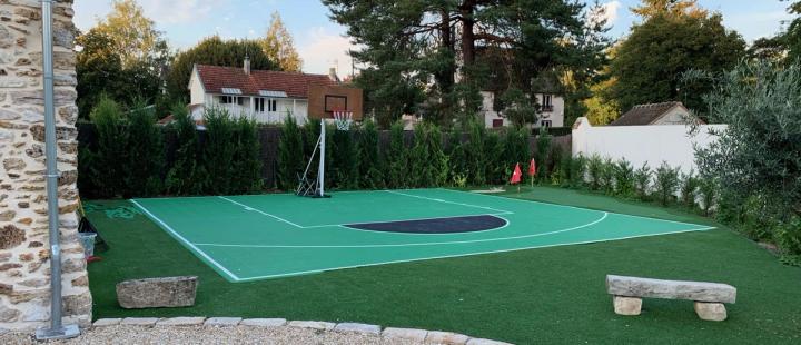 Terrain de basket en dalles vertes installé dans le jardin d'une maison