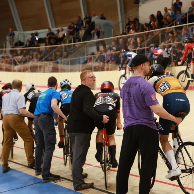 Spectators, coaches and riders gather at the rail