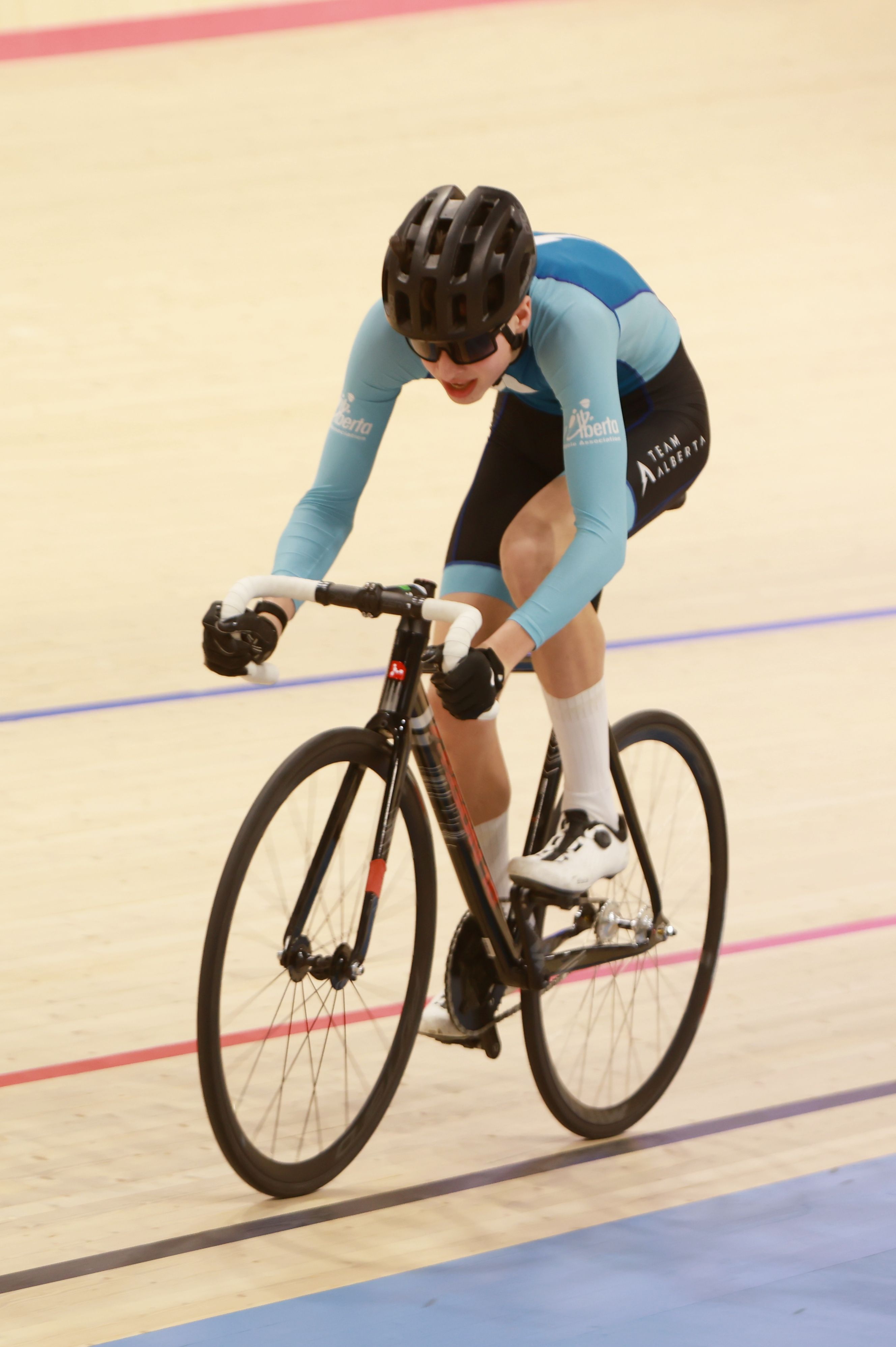 A rider in the drops, legs driving the pedals of a track bike