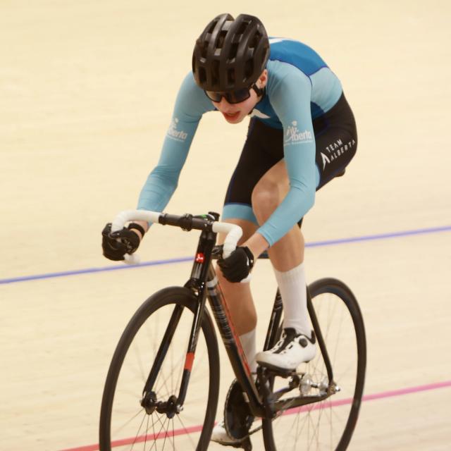 A rider in the drops, legs driving the pedals of a track bike