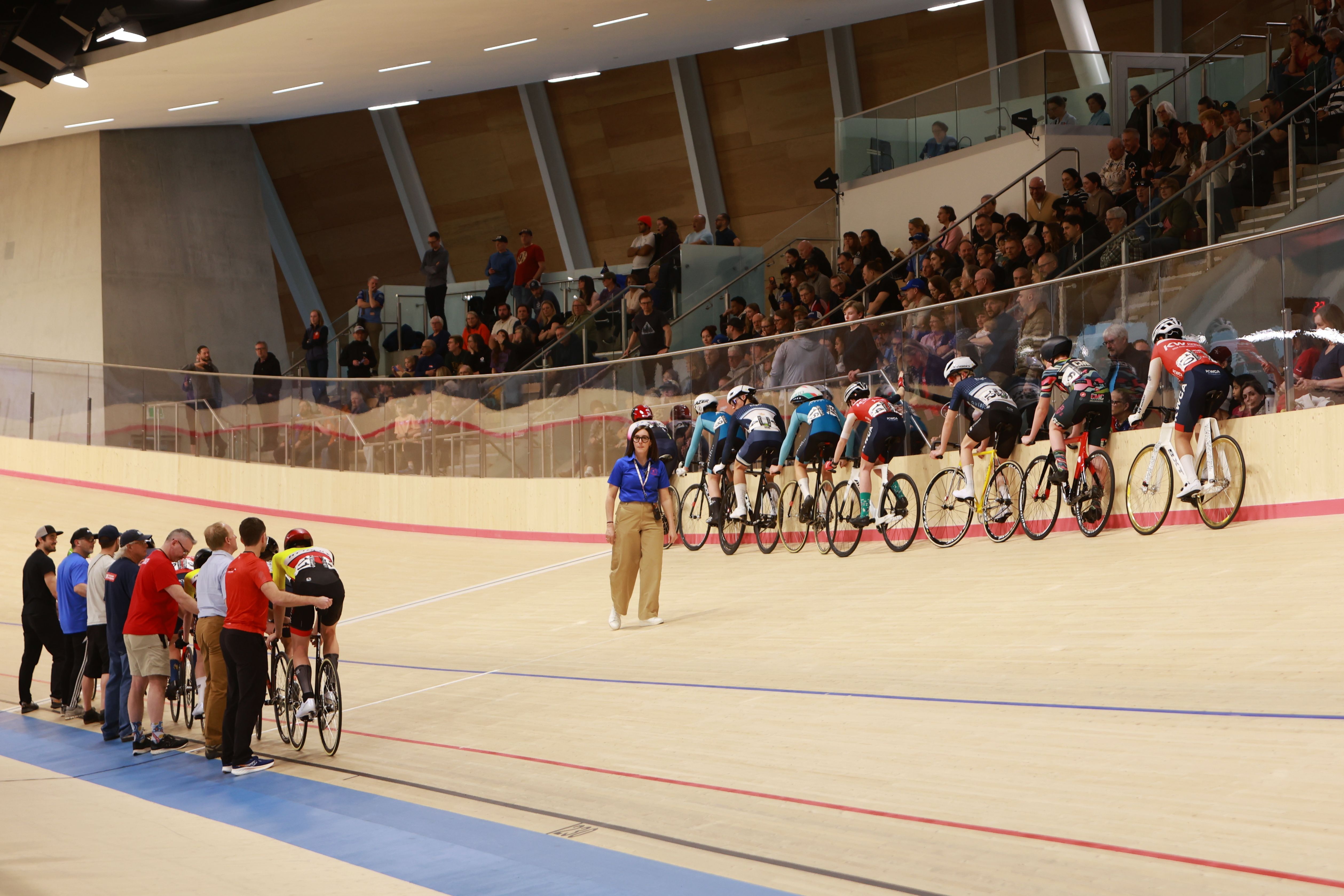 Spectators line the rail as a bunch races past at the Alberta Velodrome