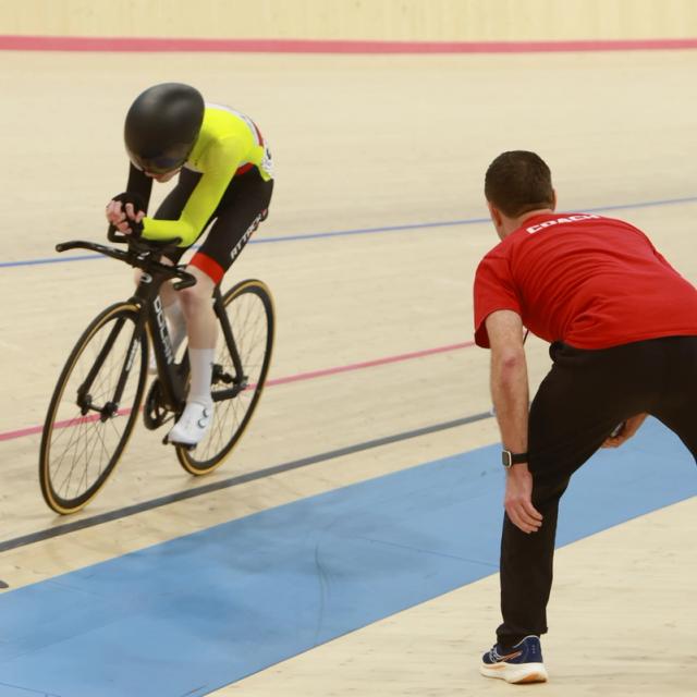 A coach steadies a young rider at the start line