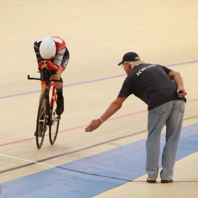 A holder steadies a rider before a standing start