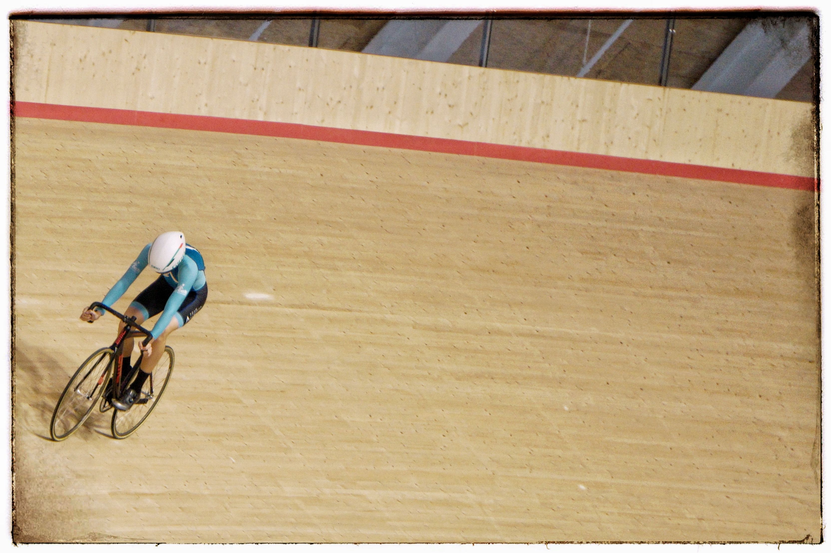 A lone rider high on the banking, seen from the level above the track