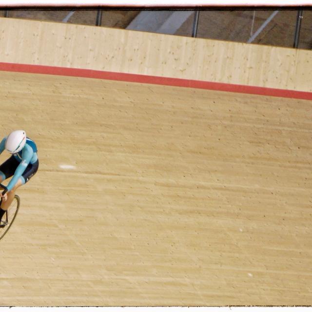A lone rider high on the banking, seen from the level above the track