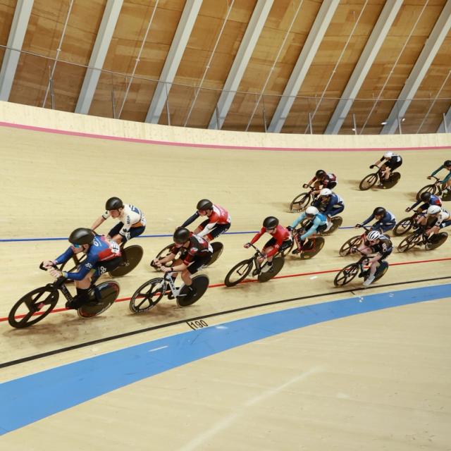 The bunch rounds the banking under the Alberta Velodrome's timber roof
