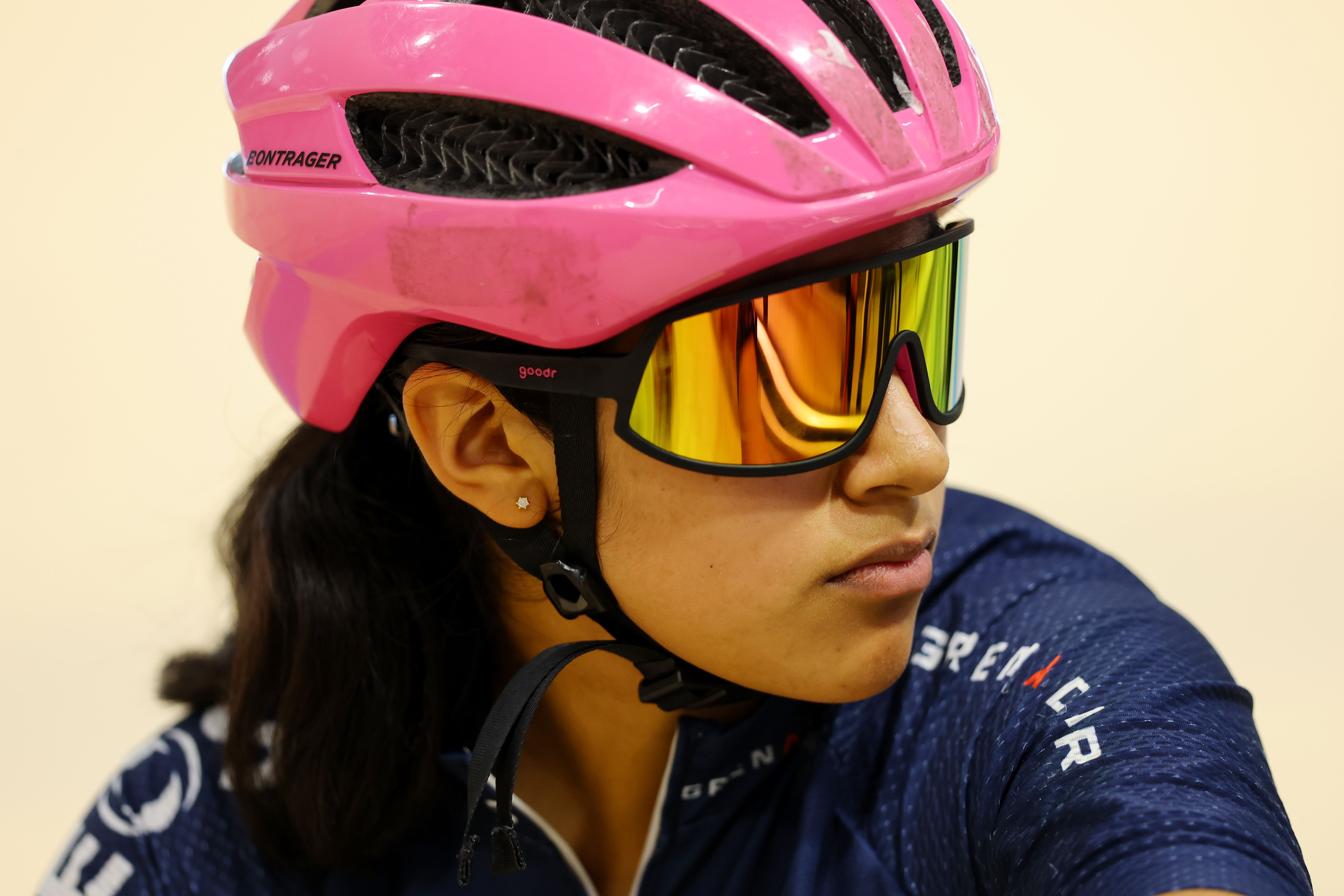 A rider in a pink helmet listens trackside during an introductory session