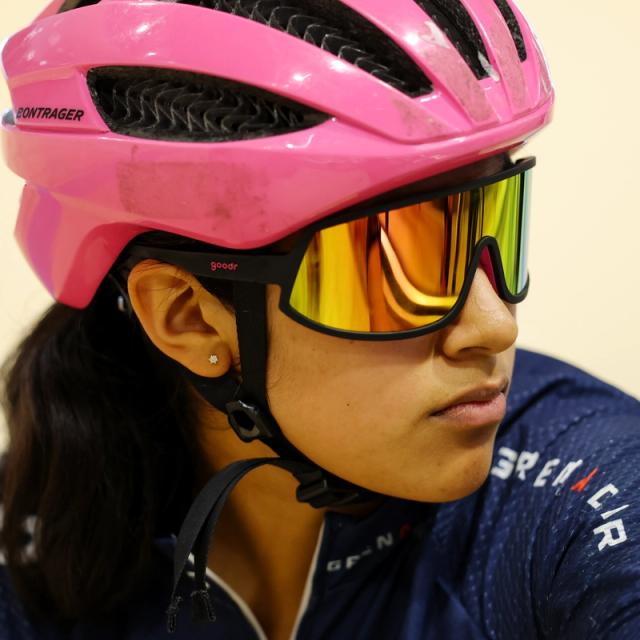 A rider in a pink helmet listens trackside
