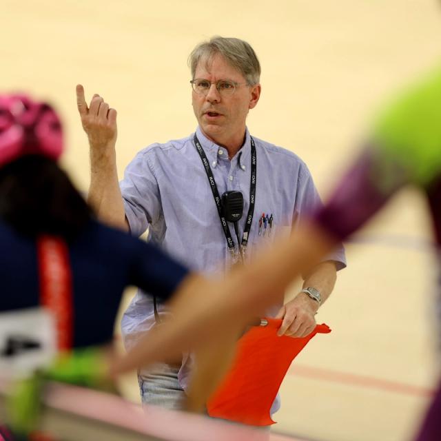 A coach explains a session to riders on the track