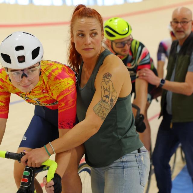 A coach steadies a first-time rider at the start line