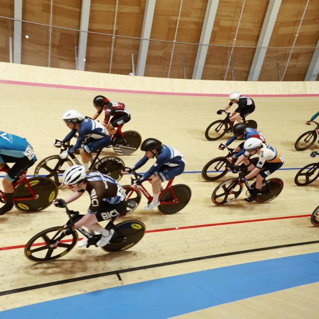 Riders sweep around the banking beneath the roof