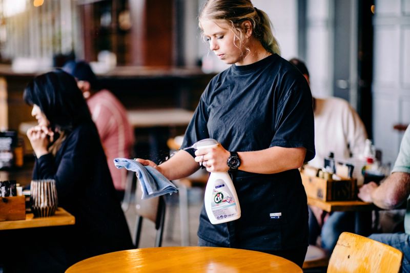 a woman is cleaning a table in a restaurant .