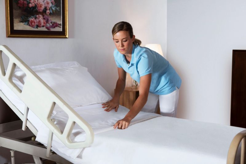 a woman is making a hospital bed in a hospital room .