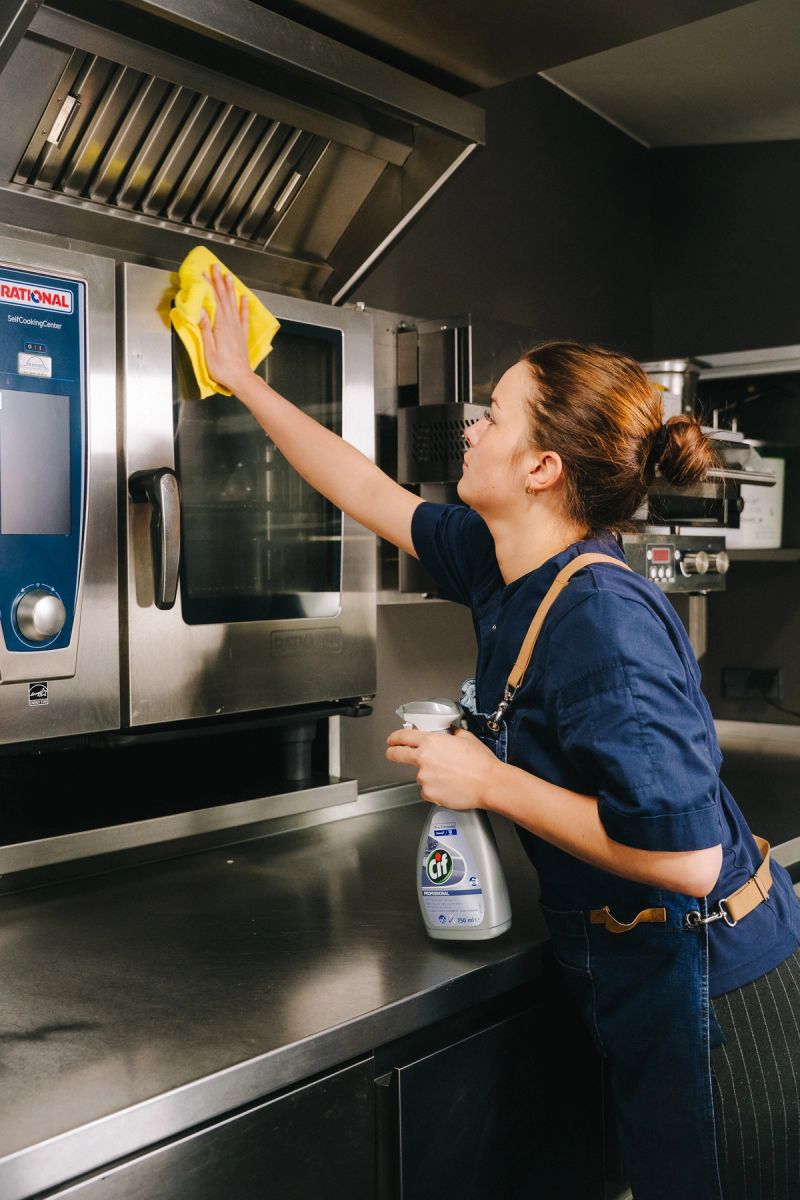 a man and a woman are cleaning a kitchen in a restaurant .