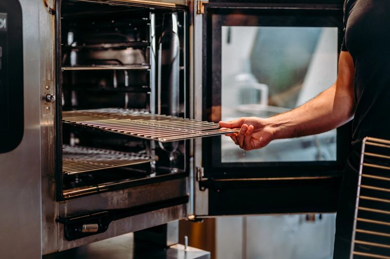 a man is taking a rack out of an oven .