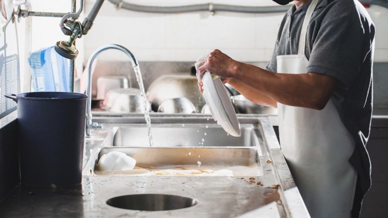 a tray of plates is sitting on top of a sink in a kitchen .