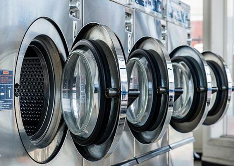 a row of washing machines are lined up in a laundromat .