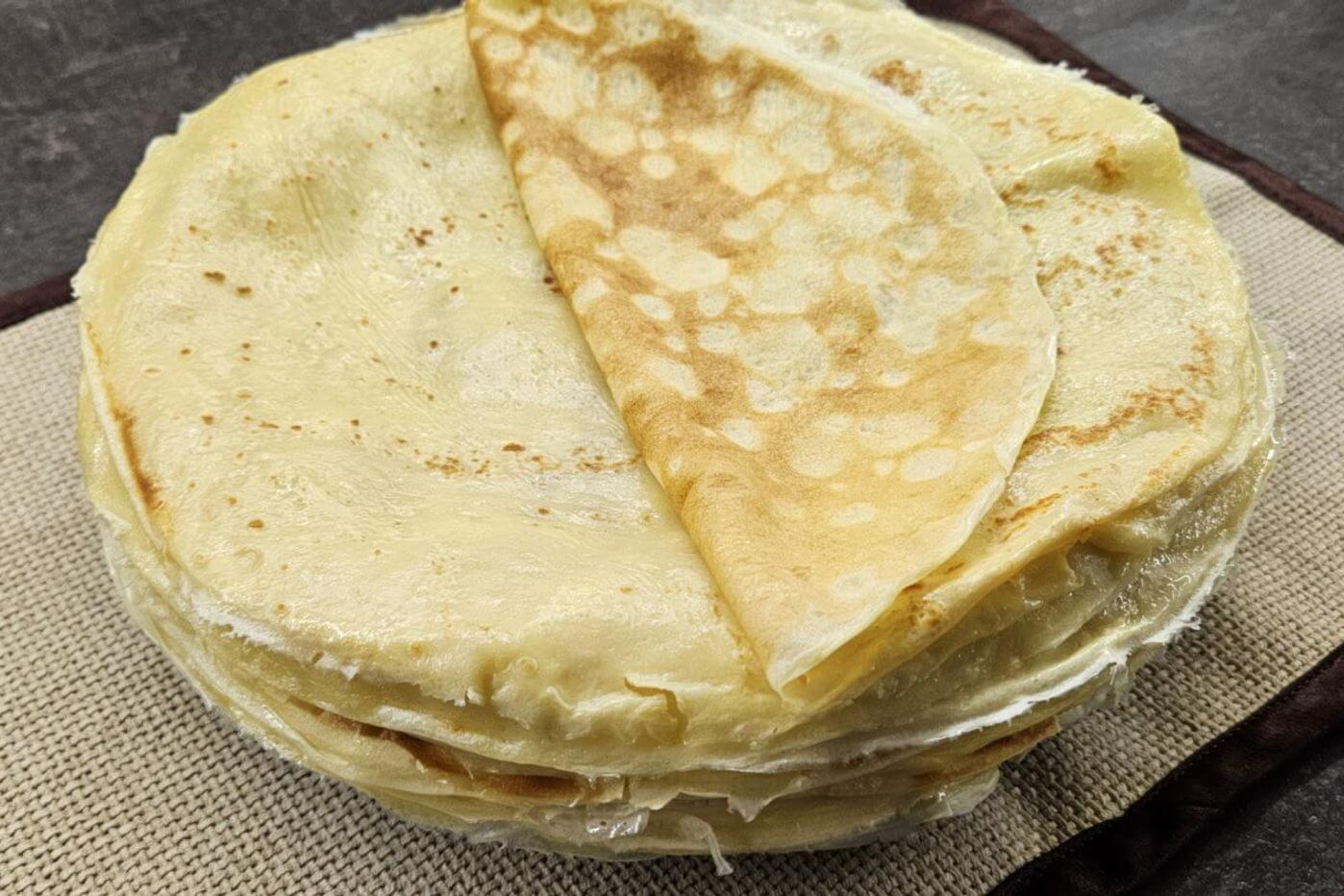 Crispy nalysnyky neatly stacked on a fabric tablecloth.