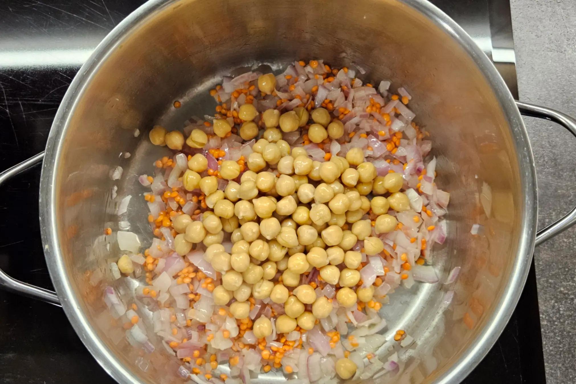 Rinsed chickpeas added to the pot with the lentils, sautéed onions, and spices.