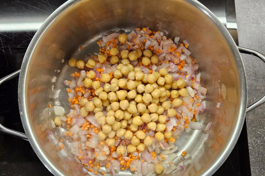 Rinsed chickpeas added to the pot with the lentils, sautéed onions, and spices.