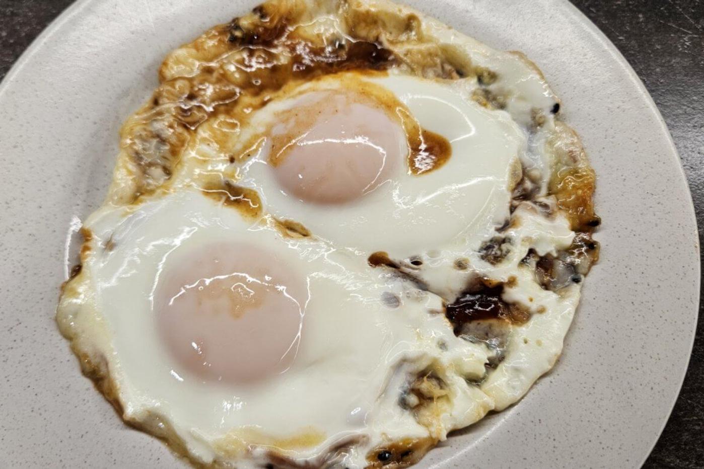 Fried eggs, served on a plate with two eggs, lightly crisped.