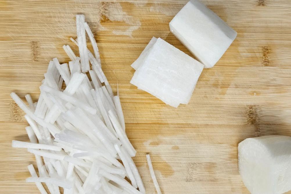 Julienned daikon radish matchsticks on a cutting board.